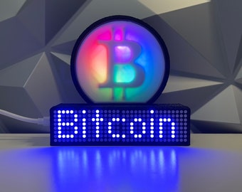 Painel de cotações de criptomoedas, ações e commodities com logotipo do Bitcoin e luzes RGB.