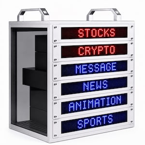 Puede incluir: Una vitrina de metal plateado con una parte delantera de vidrio transparente y un asa en la parte superior. La vitrina tiene seis pantallas LED que muestran las palabras "STOCKS", "CRYPTO", "MESSAGE", "NEWS", "ANIMATION" y "SPORTS". Dentro, cajas negras.
