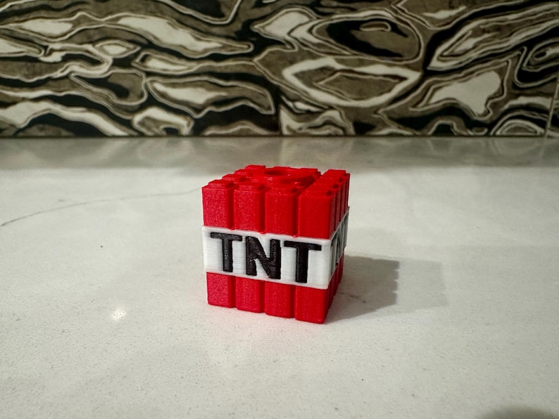 Może przedstawiać: Czerwono-biały blok z nadrukowanym napisem "TNT". Blok składa się z małych, pojedynczych blok&oacute;w połączonych ze sobą.