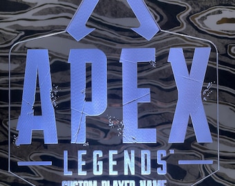May include: A white LED light with a custom player name option. The light features the Apex Legends logo with a white triangle and the words "Apex Legends" in a distressed font.