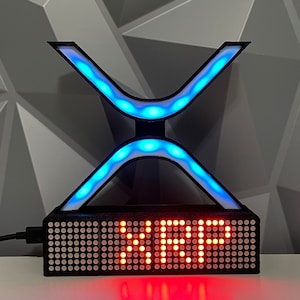 Puede incluir: Una escultura de luz LED azul y blanca con forma de la letra X con una pantalla LED roja que dice "VIP".