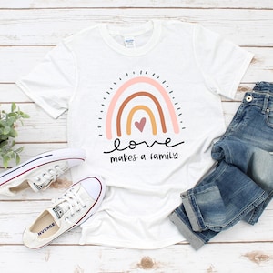 May include: White t-shirt with a rainbow design and the text "love makes a family".