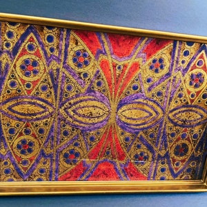 May include: A gold-framed serving tray with a colorful geometric design. The design features purple, red, and gold accents and a repeating pattern of circles and diamonds.