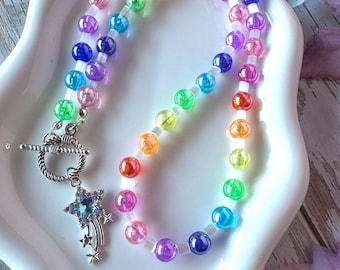 May include: A necklace featuring a strand of translucent, multi-colored beads in shades of red, orange, yellow, green, blue, and purple, separated by small clear spacers. It includes a silver-toned toggle clasp and a dangling star charm.