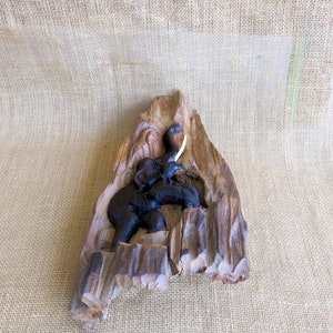K&ouml;nnte beinhalten: Eine geschnitzte Holzskulptur eines Elefanten mit einem einzigen Sto&szlig;zahn, vor einem Hintergrund aus Naturholz.