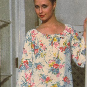 May include: A cream-coloured dress with a floral print. The dress has long sleeves and a scoop neckline with a tie. The floral pattern includes red, pink, blue, and yellow flowers.