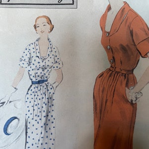 Pode incluir: Um padrão de costura vintage Vogue Special Design com duas mulheres vestindo vestidos. O vestido à esquerda é branco com bolinhas azuis e um cinto. O vestido à direita é de cor laranja sólida. Ambos os vestidos têm um decote em V e mangas curtas.