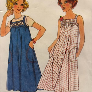 Könnte beinhalten: Eine Schnittmuster-Illustration mit zwei Kleidern. Das linke Kleid ist ein einfarbiges blaues Trägerkleid mit einem gitterartigen Brustdetail über einem weißen T-Shirt. Das rechte Kleid ist ein weißes ärmelloses Trägerkleid mit rotem Karomuster.