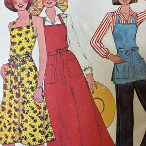 May include: A vintage sewing pattern illustration featuring three apron styles. One is a yellow floral halter apron, the second is a long red apron worn over a white shirt, and the third is a blue waist apron worn over a red and white striped shirt.