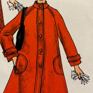 Puede incluir: Un abrigo rojo de manga larga con cuello mandarín, cierre de botones y dos bolsillos grandes. El abrigo tiene un ribete negro contrastante alrededor del cuello, los puños y los bolsillos.