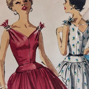May include: Two women wearing sleeveless dresses. The woman on the left is wearing a red dress with a V-neck and a bow on each shoulder. The woman on the right is wearing a white dress with a blue floral pattern and a bow on each shoulder.