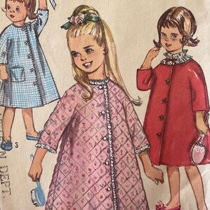 Può includere: Un modello di cucito vintage con tre ragazze che indossano abiti diversi. La ragazza al centro indossa un abito trapuntato rosa con motivo floreale e bordatura in pizzo bianco. La ragazza a sinistra indossa un abito a quadri blu e bianco. La ragazza a destra indossa un abito rosso con un colletto in pizzo bianco.