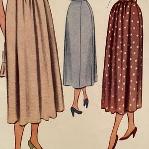May include: Three women wearing different skirts. The woman on the left is wearing a beige skirt, the woman in the middle is wearing a light blue skirt, and the woman on the right is wearing a brown skirt with white polka dots.