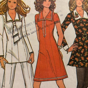 May include: A vintage sewing pattern featuring three women's dress designs. The first dress is white with a sailor collar and a tie. The second dress is red with a white collar and a white trim. The third dress is black with a floral print and a white collar.