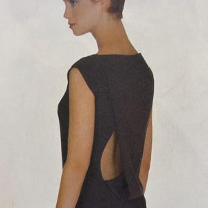 Pode incluir: Um vestido preto sem mangas com um design exclusivo de costas abertas. O vestido tem uma silhueta simples e elegante, com decote redondo e uma textura subtil. Uma peça clássica, adequada para várias ocasiões.