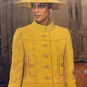 May include: A bright yellow jacket with a high collar, long sleeves, and a front button closure featuring five visible buttons. The jacket includes two rectangular front pockets with button accents and a matching wide-brimmed yellow hat.