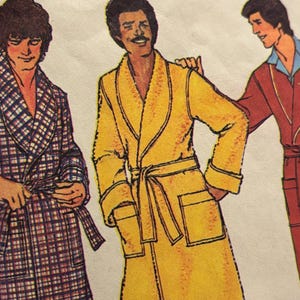 Może przedstawiać: Ilustracja trzech osób w szlafrokach. Szlafrok po lewej stronie ma wzór w kratę w odcieniach niebieskiego, czerwonego i białego. Środkowy szlafrok jest żółty z pasującym paskiem. Szlafrok po prawej stronie jest czerwony.