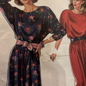 May include: Illustration of two dresses. One is a navy blue dress with a floral pattern, a pink belt, and long sleeves. The other is a red dress with a black belt and short sleeves.