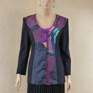 May include: A black blazer with a purple, blue and green abstract patterned panel on the front. The blazer has a button closure and long sleeves.
