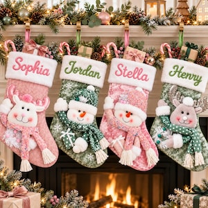 May include: Four Christmas stockings hanging in a row, each with a white cuff embroidered with the names Sophia, Jordan, Stella, and Henry. The stockings feature plush reindeer and snowman characters, patterned fabric, and small gift box accents.