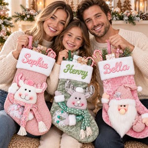 May include: Three personalized Christmas stockings featuring plush characters. The left stocking is pink with a reindeer and the name Sophia. The center stocking is green with a reindeer and the name Henry. The right stocking is pink with a Santa and the name Bella.