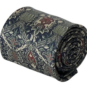 Op de afbeelding: Een opgerolde stropdas met een bloemenpatroon in tinten groen, rood en blauw op een crèmekleurige achtergrond.