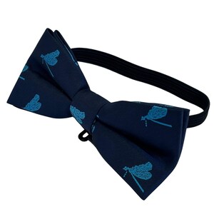May include: A navy blue bow tie with a blue dragonfly pattern. The bow tie has an adjustable elastic strap.