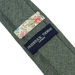 May include: A green linen tie with a floral patterned label and a navy blue label that reads "Frederick Thomas London".