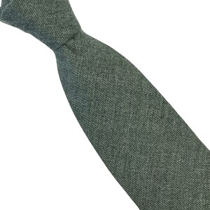 May include: A dark green linen tie. The tie is made of a textured fabric and has a narrow width.