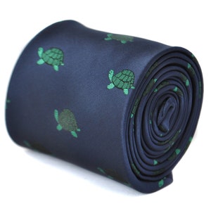 May include: A navy blue tie with a repeating pattern of green sea turtles. The tie is rolled up and ready to be worn.