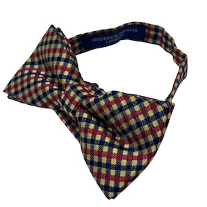 Può includere: Un papillon a quadri rossi, gialli e blu con il testo "FREDERICK THOMAS LONDON" sul retro.