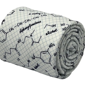 Op de afbeelding: Een witte stropdas met een blauw en wit chemisch formulepatroon. De stropdas is opgerold en het patroon is zichtbaar aan de buitenkant van de rol.