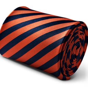 Puede incluir: Una corbata a rayas con rayas diagonales de color naranja y azul marino. La corbata está enrollada y las rayas son visibles en el exterior del rollo.