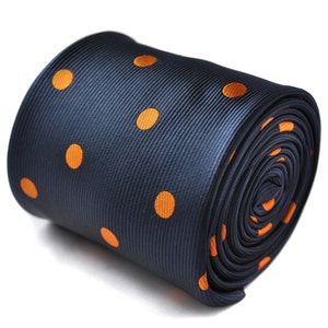 May include: Rolled navy blue tie with orange polka dots. The tie is made of a smooth fabric and is rolled up, showcasing the pattern. The orange dots are evenly spaced across the navy background, creating a classic design.