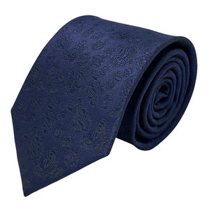May include: A dark blue patterned tie with a paisley design. The tie is rolled up and ready to be worn.