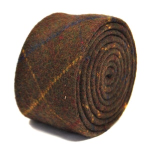 May include: Rolled brown tweed tie with a plaid pattern featuring yellow, blue, and red accents. The tie is made of a textured fabric and is tightly rolled, showcasing its pattern and material.