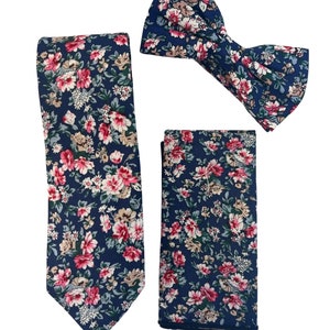 May include: A navy blue tie, bow tie, and pocket square set with a pink and white floral pattern.