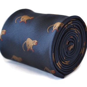 Puede incluir: Una corbata de seda azul marino con un patrón repetido de monos marrones. La corbata está enrollada y el patrón es visible en el exterior del rollo.
