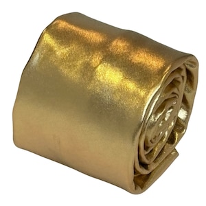 Könnte beinhalten: Eine aufgerollte goldene Satin-Krawatte. Die Krawatte ist einfarbig mit einem leichten Glanz.