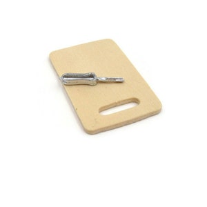 May include: A miniature wooden cutting board with a small silver knife on top.