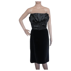 Könnte beinhalten: Ein schwarzes, trägerloses Kleid mit einem Satin-Oberteil und einem Samt-Rock. Das Oberteil hat eine geraffte Detail und eine figurbetonte Silhouette. Der Rock ist knielang und hat einen geraden Schnitt.