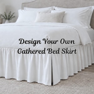 May include: A white gathered bed skirt featuring a ruffled design that drapes around the base of a bed. The text "Design Your Own Gathered Bed Skirt" is overlaid on the image. The bed is dressed in white bedding with multiple pillows.