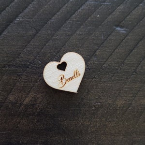 May include: A white wooden heart-shaped tag with the name "Benolli" engraved on it.