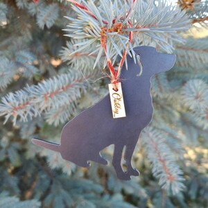 May include: A black metal dog silhouette Christmas ornament with a gold tag that reads "Oakley".
