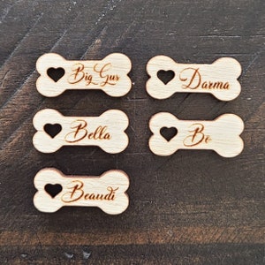 May include: Five wooden dog bone-shaped tags with heart cutouts and personalized names: Big Gus, Darma, Bella, Be, and Beaudi.