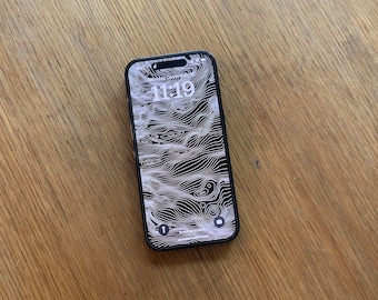 Peut inclure: Un smartphone noir avec un motif de carte topographique blanche sur l'écran. L'heure est 11h19.