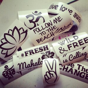 May include: Assortment of stickers with various designs and phrases, including "Follow Me to the Beach", "Wild & Free", "#Fresh", "Mahalo", "Om", and a peace sign.