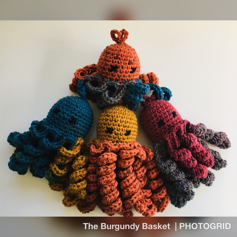 May include: Four crocheted octopus plushies in different colors: teal, mustard yellow, burnt orange, and burgundy. Each octopus has a smiling face and eight tentacles.