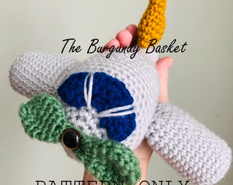 Può includere: Schema all'uncinetto per un giocattolo amigurumi di aereo grigio con un'elica blu e bianca, ali verdi e una coda gialla. Lo schema si chiama "The Burgundy Basket".
