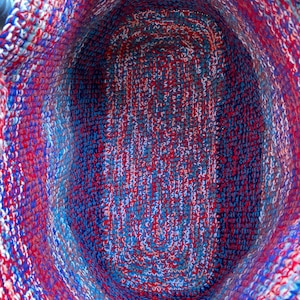 Pu&ograve; includere: Un cesto all'uncinetto con un motivo rosso, bianco e blu. Il cesto &egrave; vuoto e l'interno &egrave; visibile.